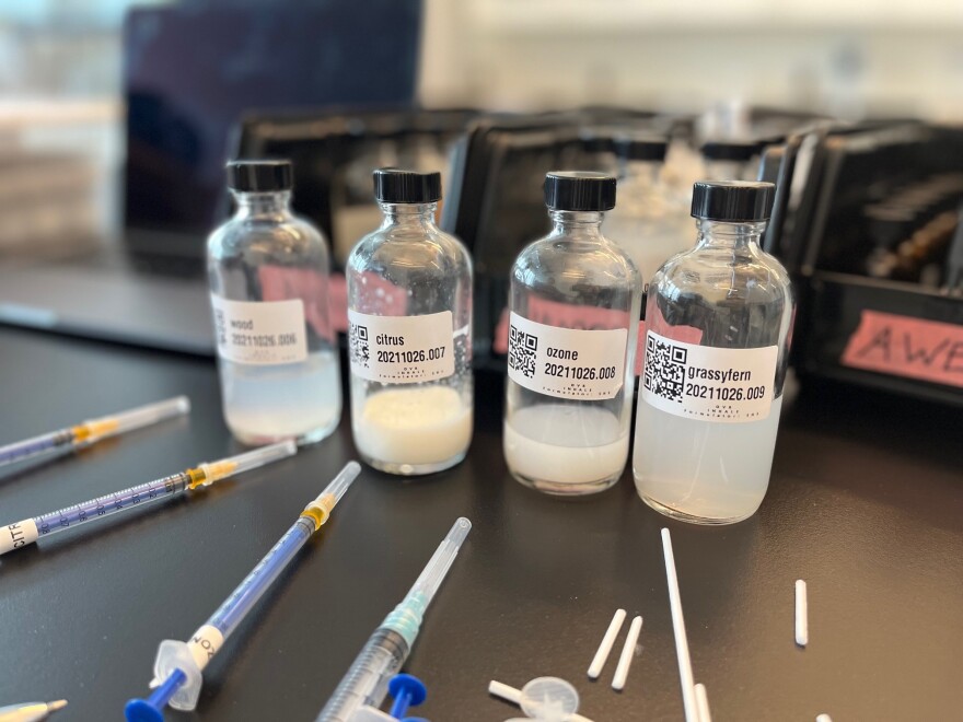 Four glass bottles sit on a table next to pipettes.