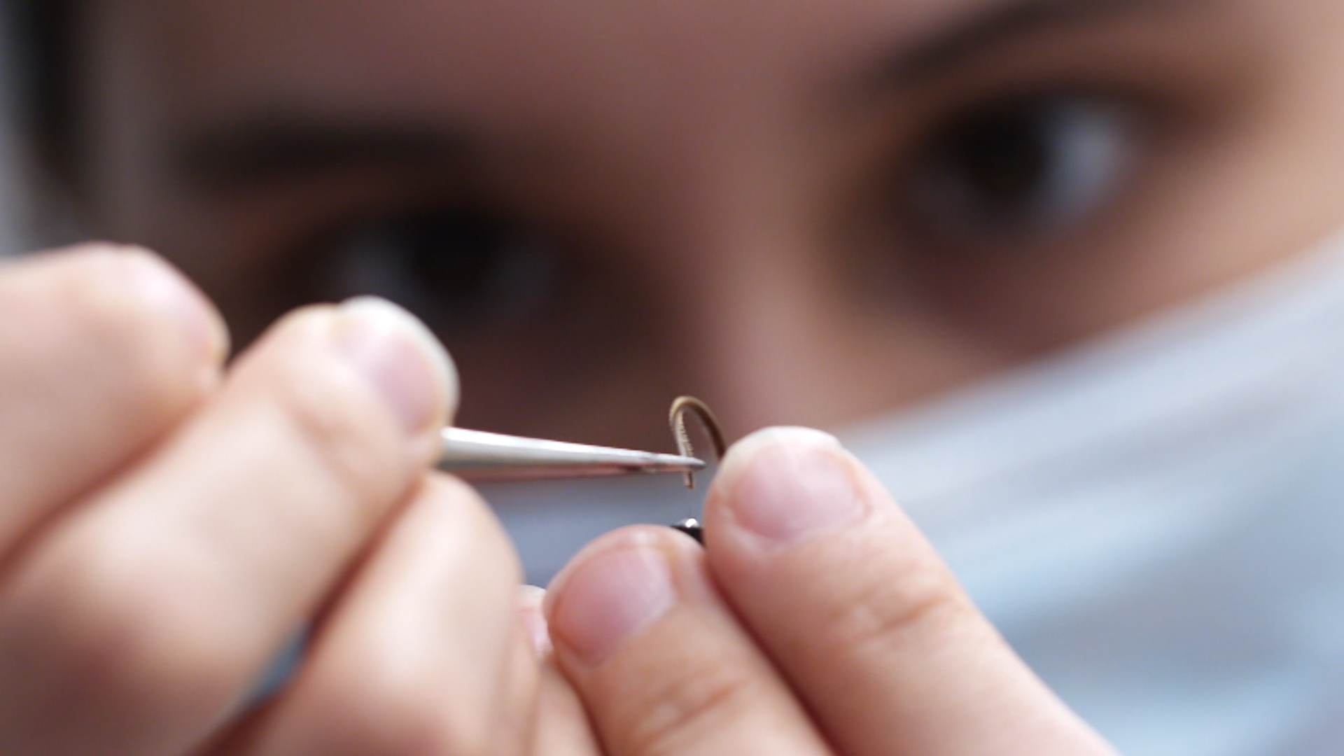 UW engineer Melanie Anderson carefully threads a moth antenna onto a circuit. The hair-like wires slide perfectly into the hollow tube of the antenna.