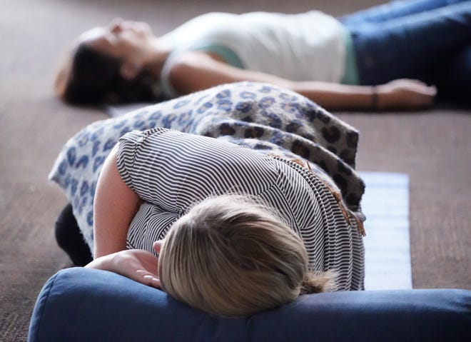 Participants get comfortable as facilitator Sarah Gardner leads a group sound bath session on Wednesday, July 13, 2022, at the Maven Space social an co-working club in Indianapolis. 