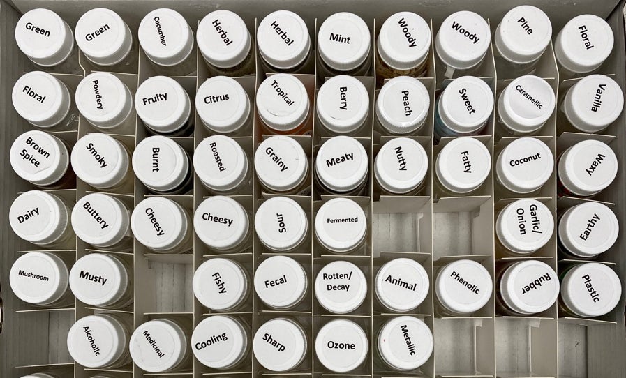 Vials with white caps, each with a black label of the smell sample it contains.