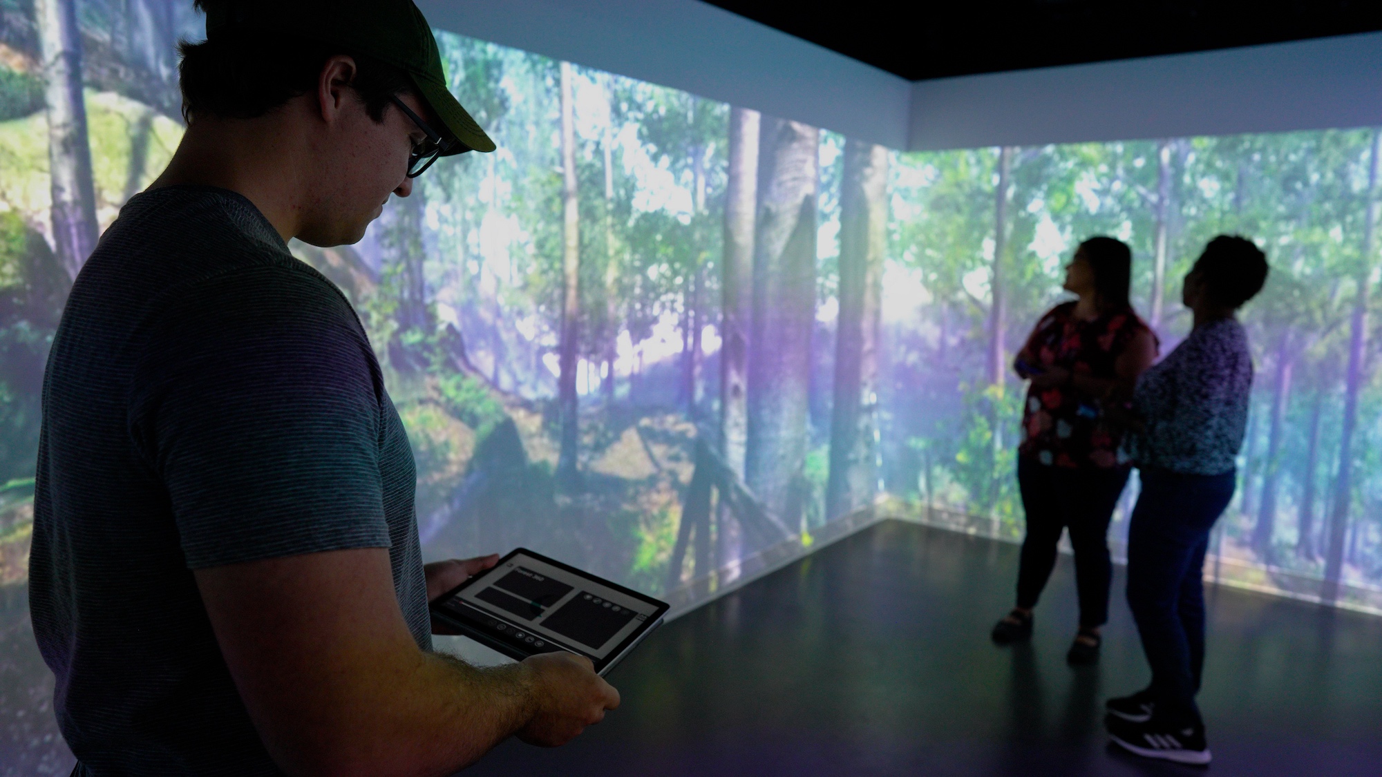 UC Davis graduate student in shadow uses a tablet to control special effects of the room with 360 degree video surrounding him.