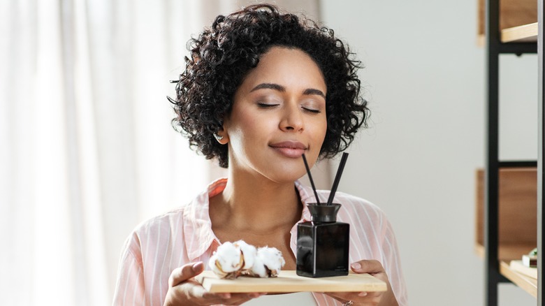 african american woman with curly hair smelling reed diffusers 