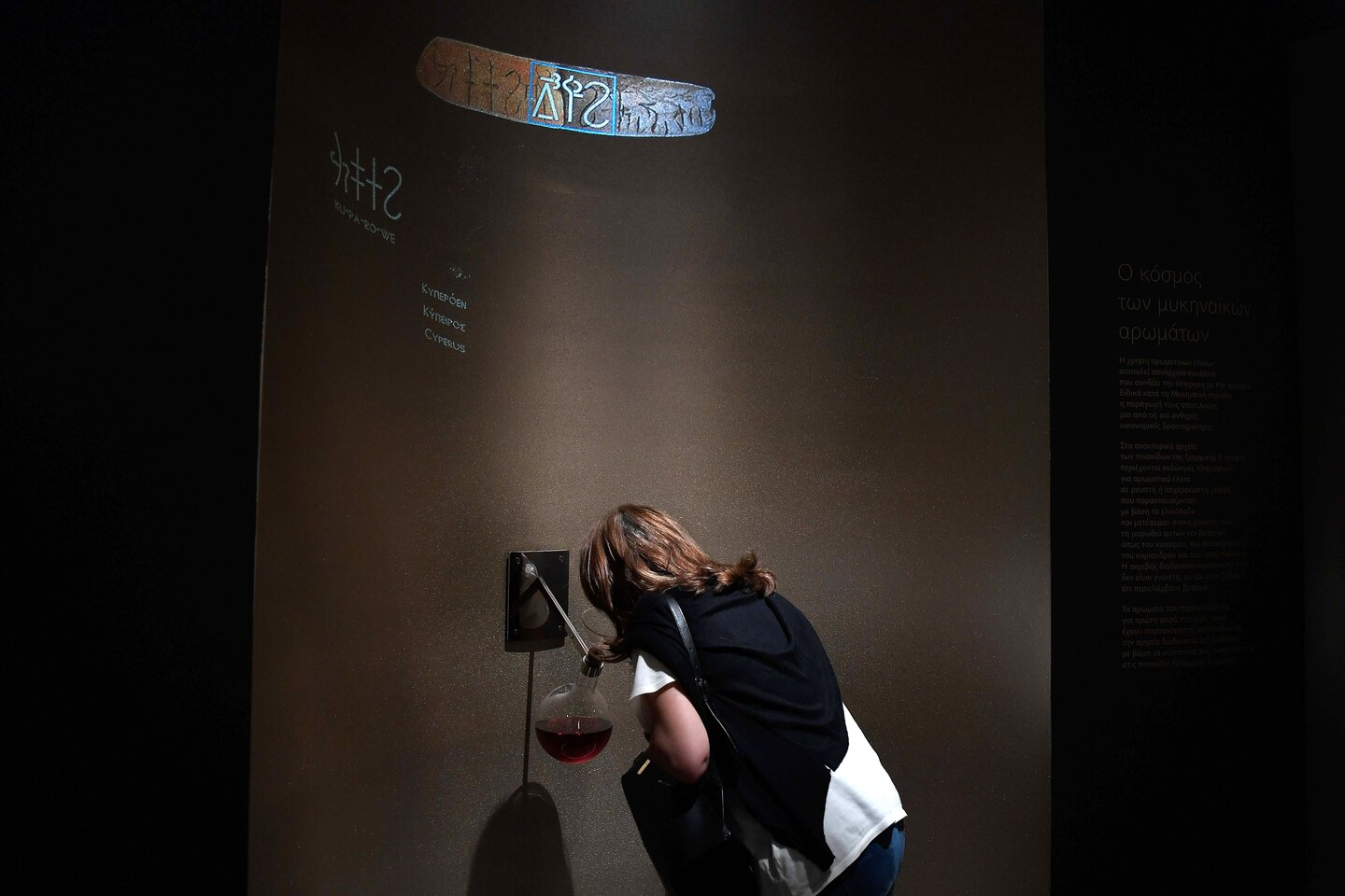 A woman smells a perfume made from a formula from antiquity at the new temporary exhibition at the National Archaeological Museum in Athens